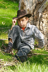 boy sitting against a tree in the Australian outback